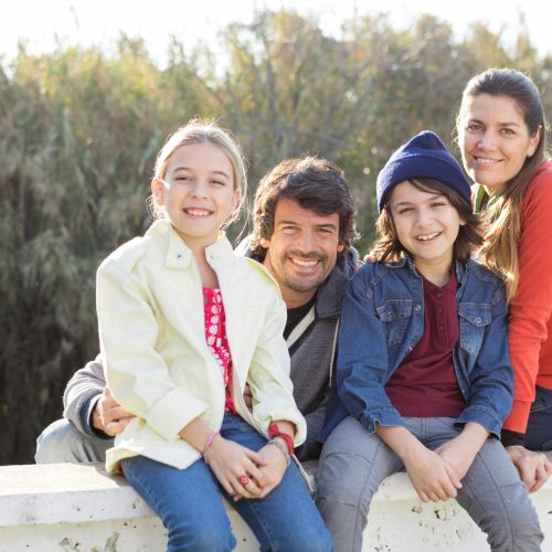 smiling-siblings-sitting-with-their-parents